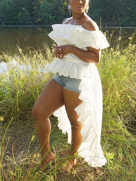 Woman wearing a white off-shoulder tiered ruffle blouse with a high-low hem outdoors by a lake.