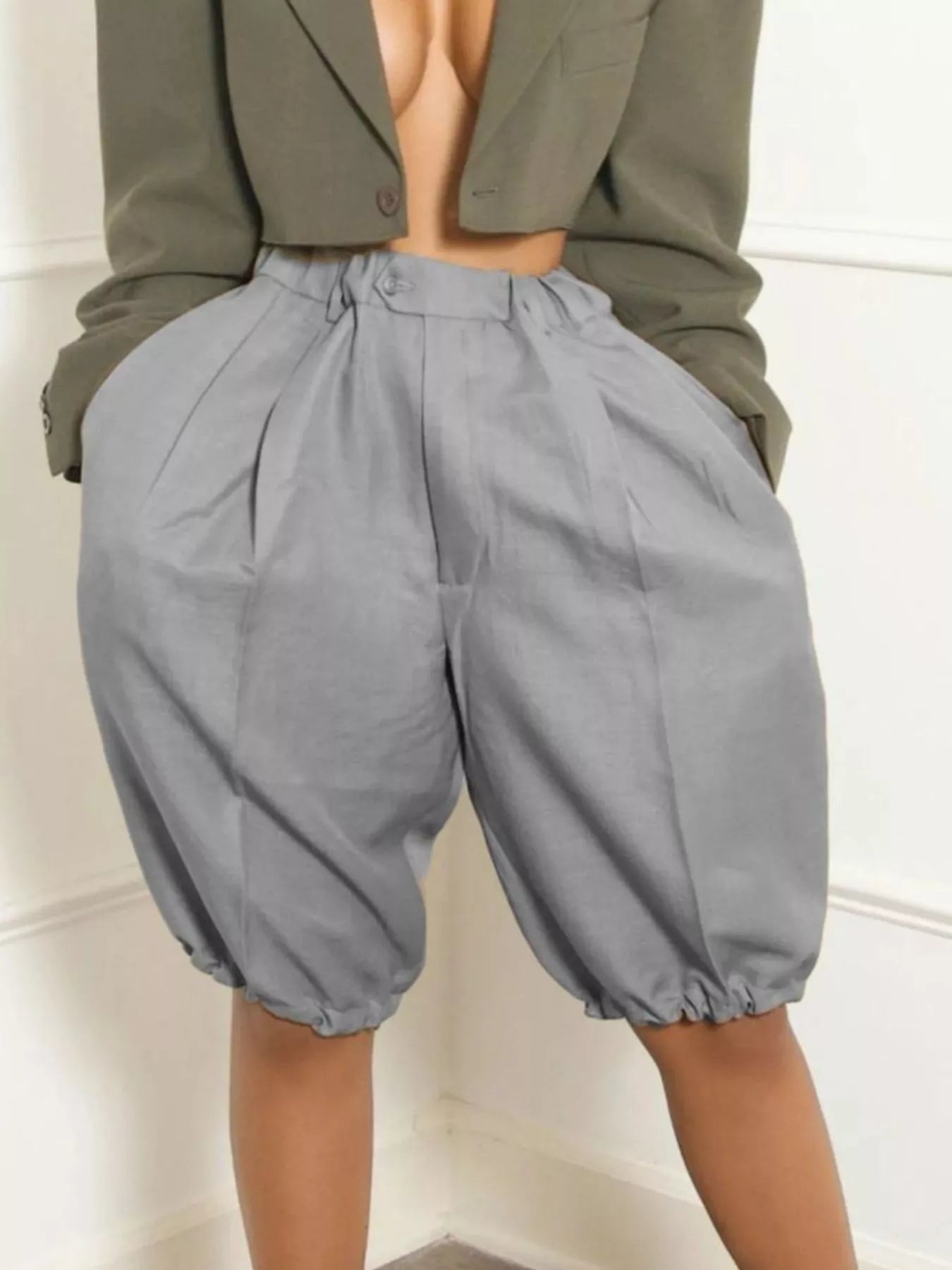 Gray pleated high-waist shorts with pockets and elastic cuffs.
