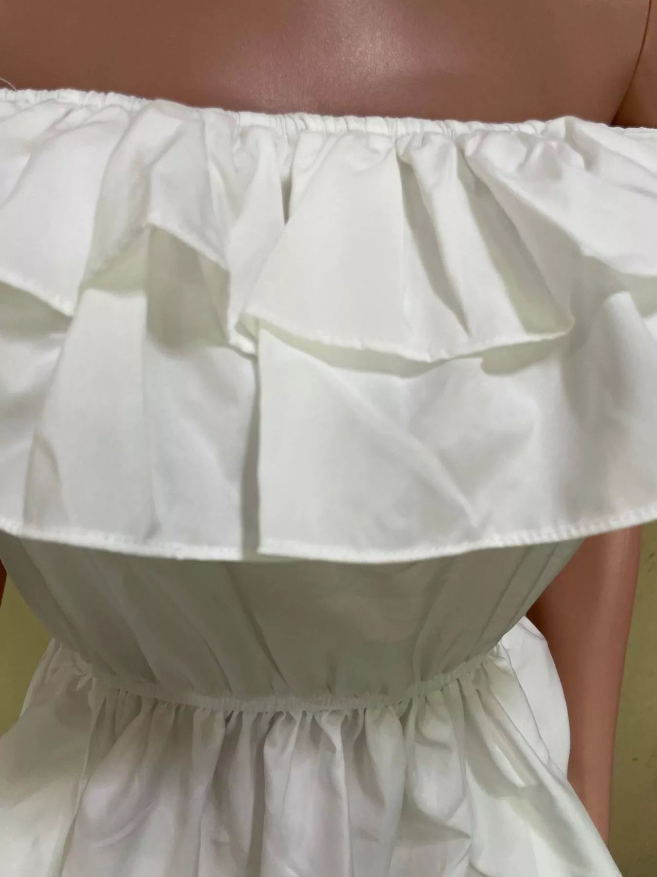White off-shoulder blouse with tiered ruffles and high-low hem; elastic neckline, no stretch, polyester-spandex blend.